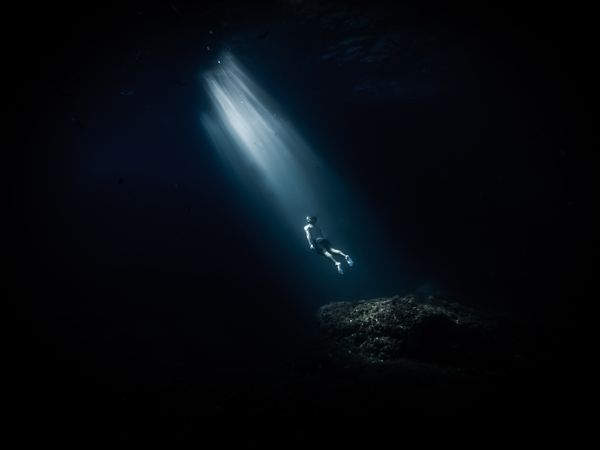 Underwater shot of person diving in ocean depth