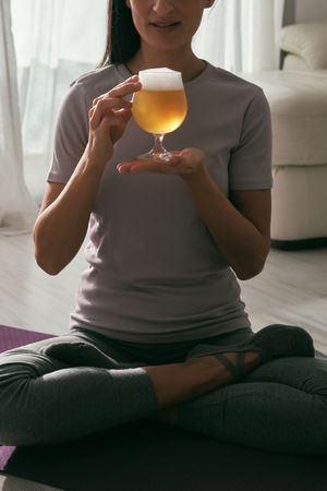 Anonymous woman with beer during yoga session