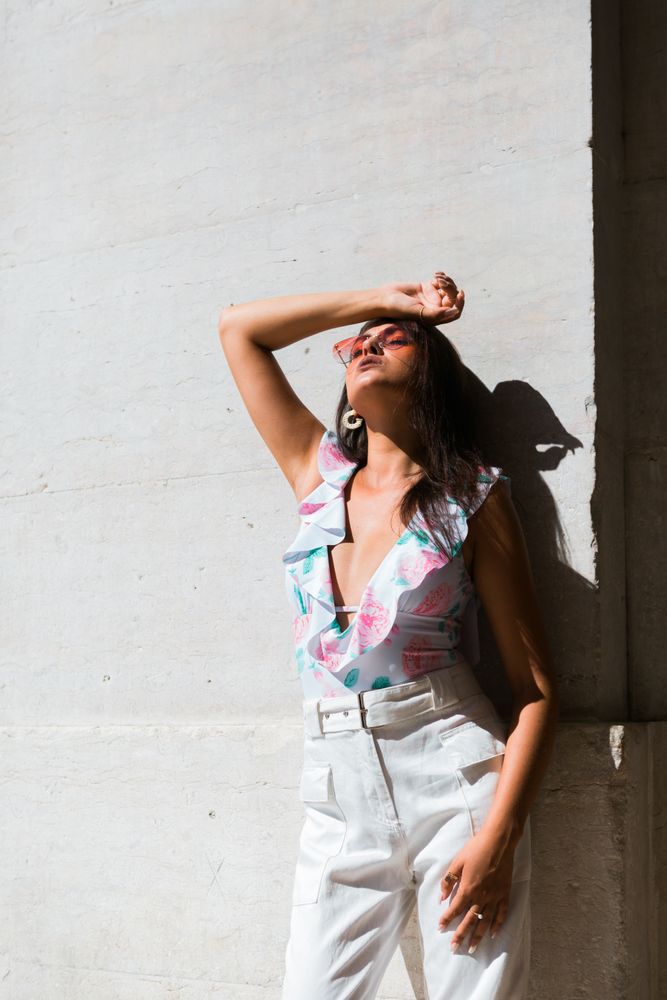 Dreamy stylish woman in sunglasses standing on city street