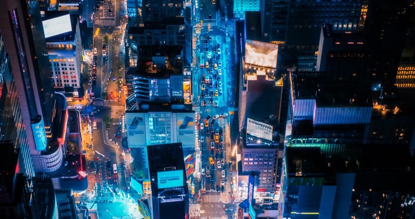 Night Aerial Shot of New York City with Skyscraper Spires and Straight Busy Streets with Cars and Yellow Taxi Vehicles. Top Down Helicopter View of Office Buildings in a Big Urban Center