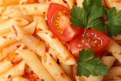 Tasty pasta with tomato and parsley on whole background, close up