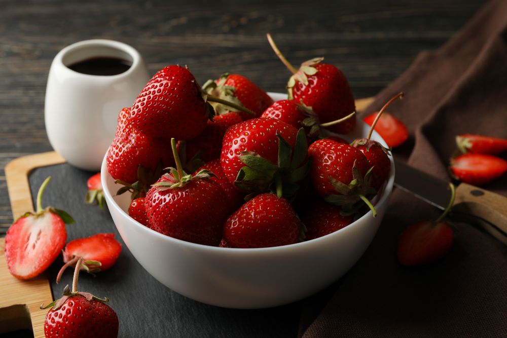 Composition with bowl of tasty strawberry on wooden table. Summer berry