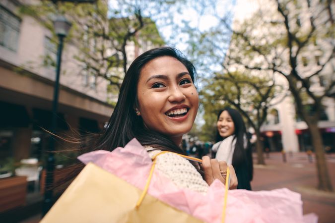 Asian woman with shopping back smiling over shoulder