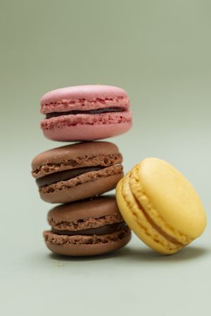 Chocolate, strawberry & lemon macaroons on a green table, vertical with copy space