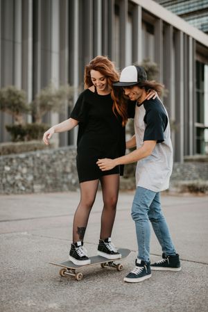 Man helping girlfriend to skate on road