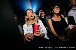 Young people laughing while watching film in movie theater 4MNOqb