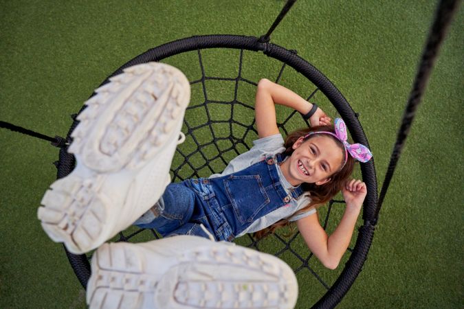 Excited girl having fun on web swing
