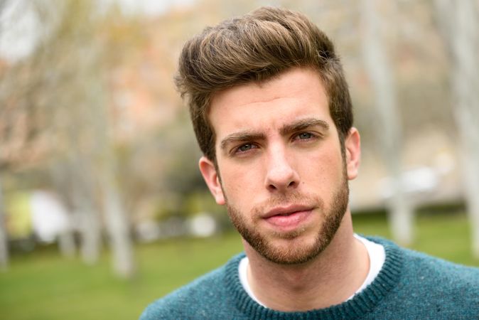 Close up of white male’s serious face standing in park