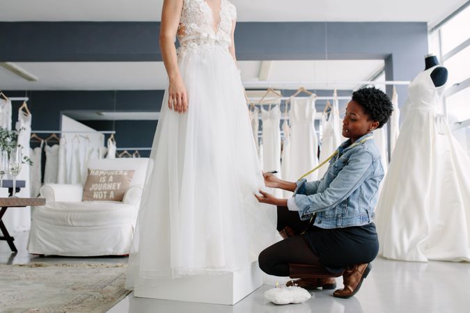 Black female making adjustment to wedding gown in fashion designer studio