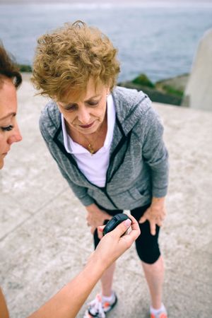 Mature woman looking smart watch with her coach
