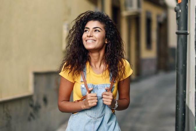 Arab woman standing in the street in denim dress looking up, copy space