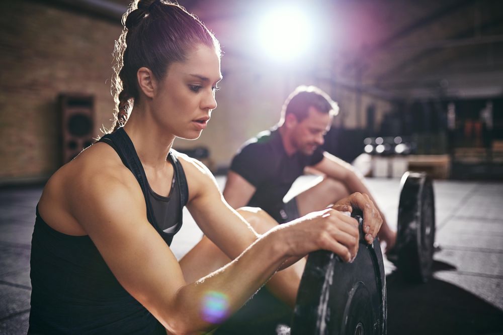 Close up of young fit woman holding weight plate as she takes a rest
