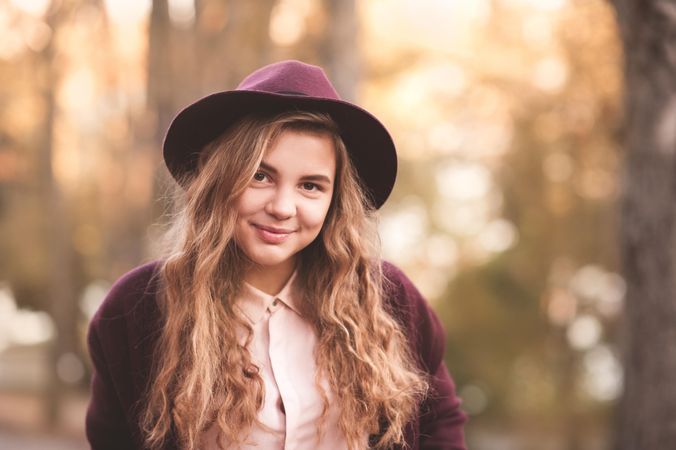 Portrait of happy teenage girl with purple hat standing outdoor