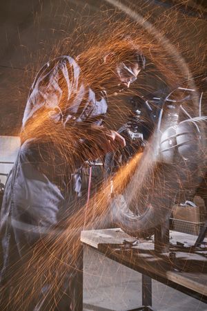 Man standing at workbench and repairing motorbike in workshop