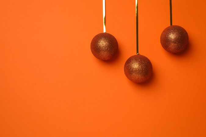 Christmas balls on orange background, space for text