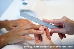 Beautician filing nails of a customer 5kkAP5