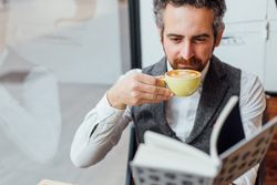 Man with coffee in cafe while reading book