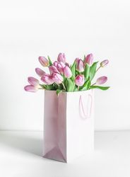 Bunch of pink blooming tulips in gift box on table