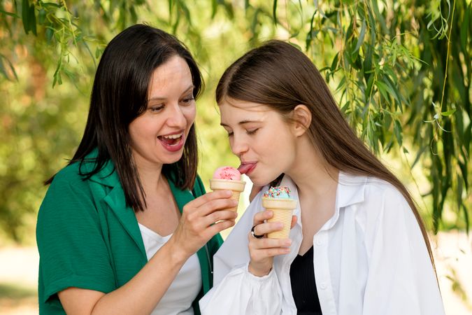 Mom and teenage daughter eat ice cream on walk