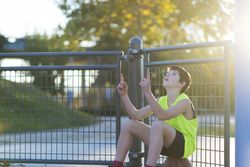 Teen sitting outdoors on basketball at a public court