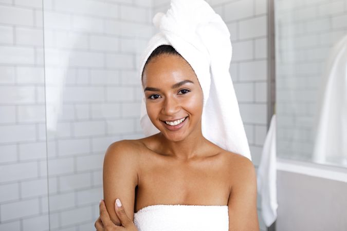 Smiling Black woman in towels after a shower in bright bathroom