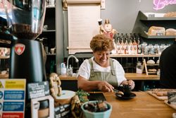 Older Black woman putting cookie with coffee