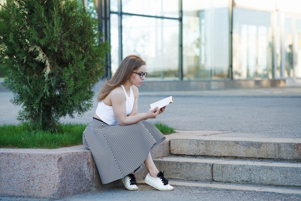 Curious woman in glasses reading outside