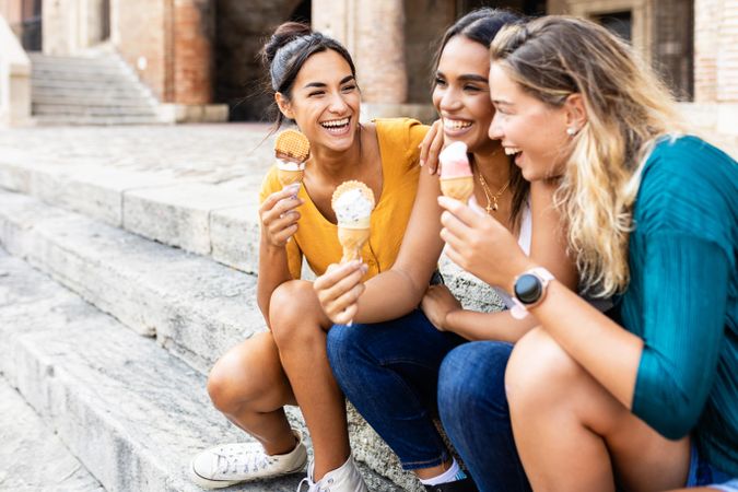 Female friends sitting on steps outside with ice cream