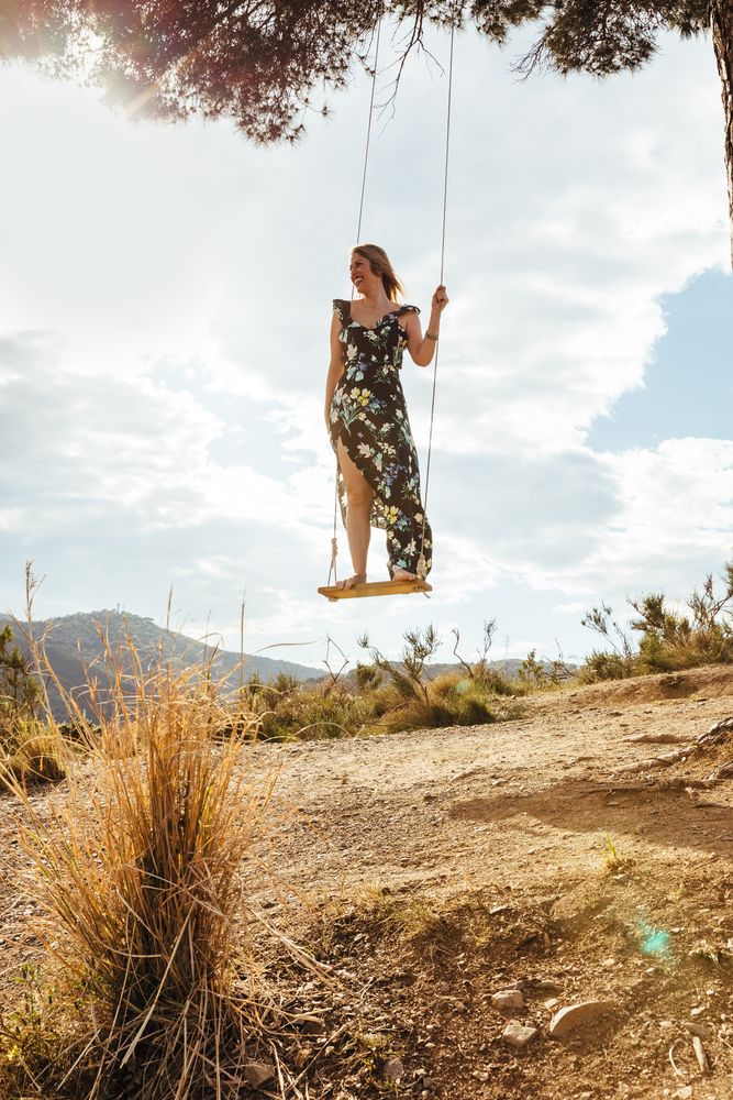 Happy female enjoying on a swing at sunset