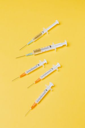 Top view of five syringes on yellow background