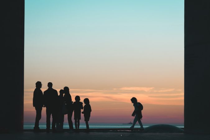 Silhouette of family standing on beach during sunset
