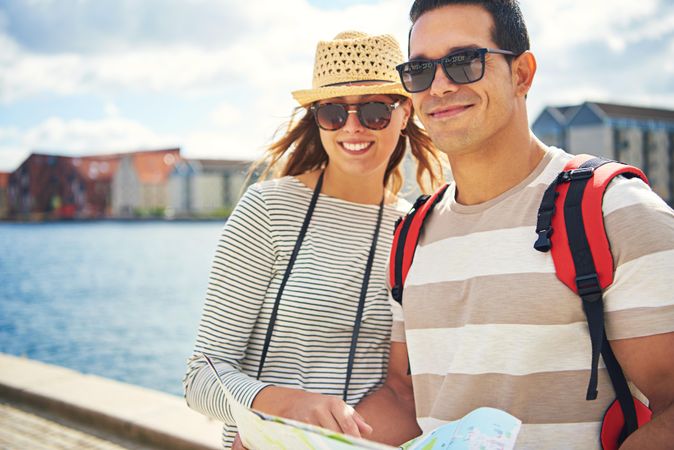 Smiling happy couple on the water front with a map