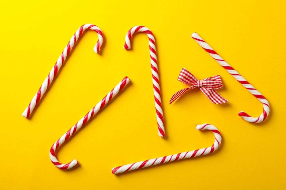 Composition with sweet candy canes on color background, space for text