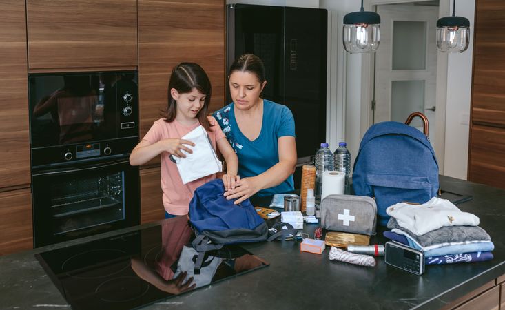 Mother preparing emergency backpack with her daughter