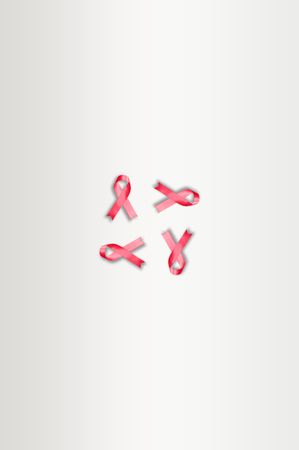 Four pink ribbons on plain background