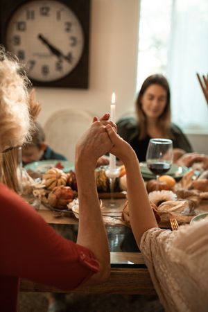 Cropped image of people holding hands and praying before dinner