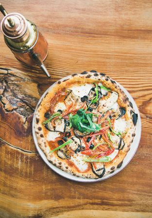 Freshly made wood fire oven pizza with olive oil on the wide, on wooden table
