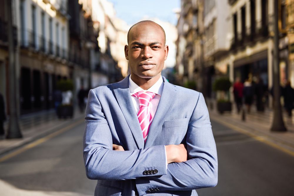 Male standing with his arms crossed on quiet street
