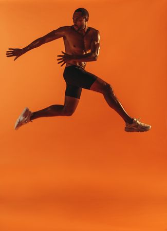 Male fitness model jumping in mid-air and twisting to his side