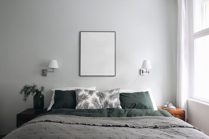 Vertical picture frame mockup above bed on sage wall