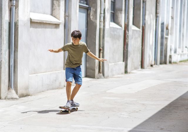 Front view of teenage boy skateboarding on street on a sunny day