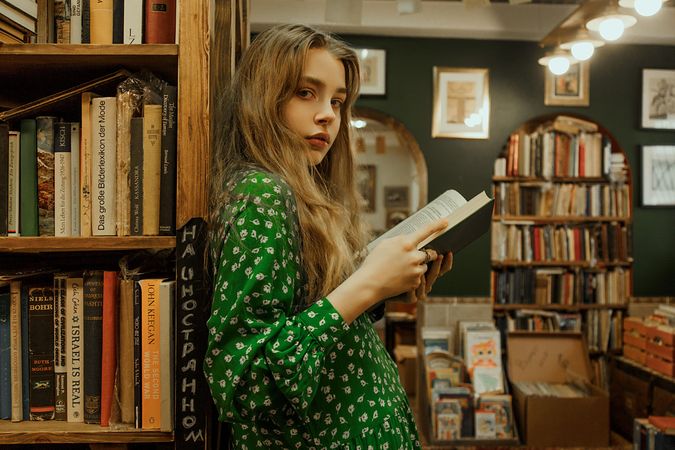 Girl holding a book and standing in library
