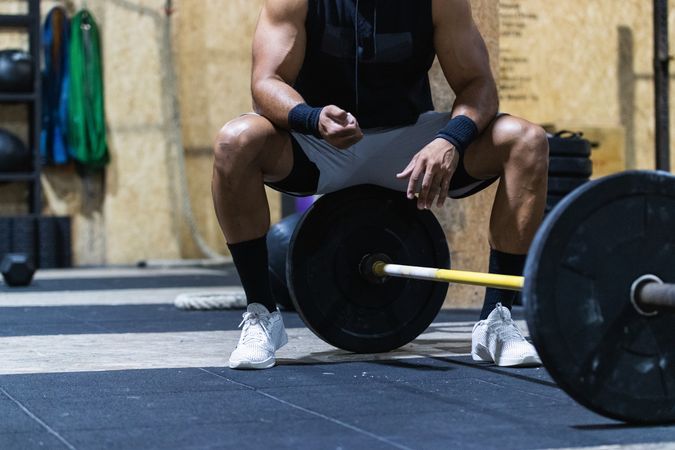 Strong anonymous sportsman near barbell