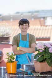 Young smiling teenager wearing gardening apron while standing on patio 5RVpnJ