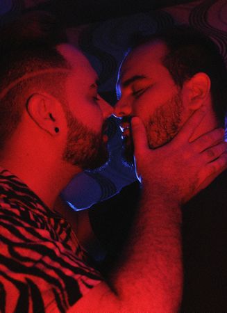 Two men kissing in red lit room