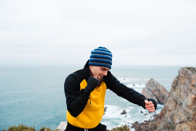 Kickboxer training on cliff near sea