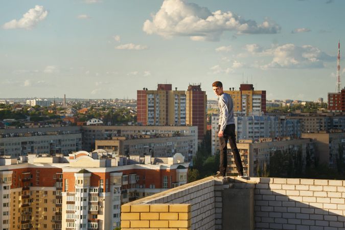 Male balancing on wall high above city