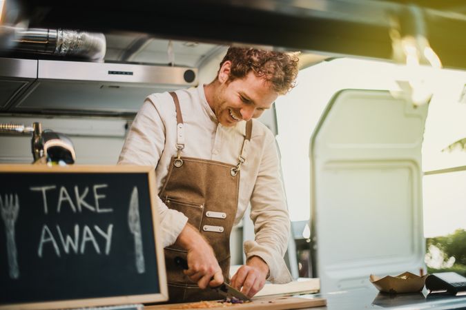 Young chef cooking inside vegan food truck restaurant - Focus on face