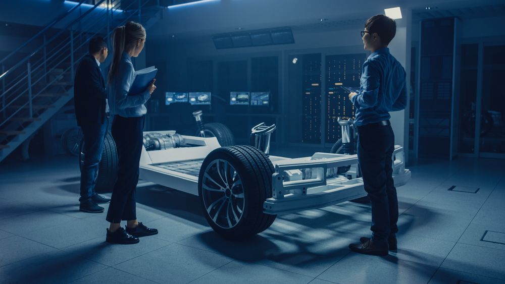 Automobile Engineers Working on Electric Car Platform Chassis, Using Tablet Computers with CAD Software for 3D Concept