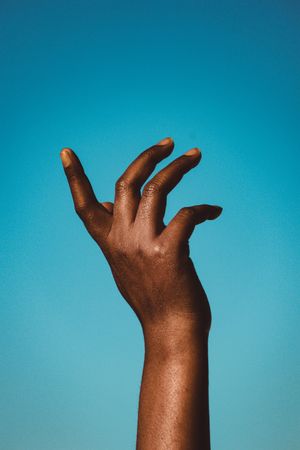 Cropped image of Black hand against blue background